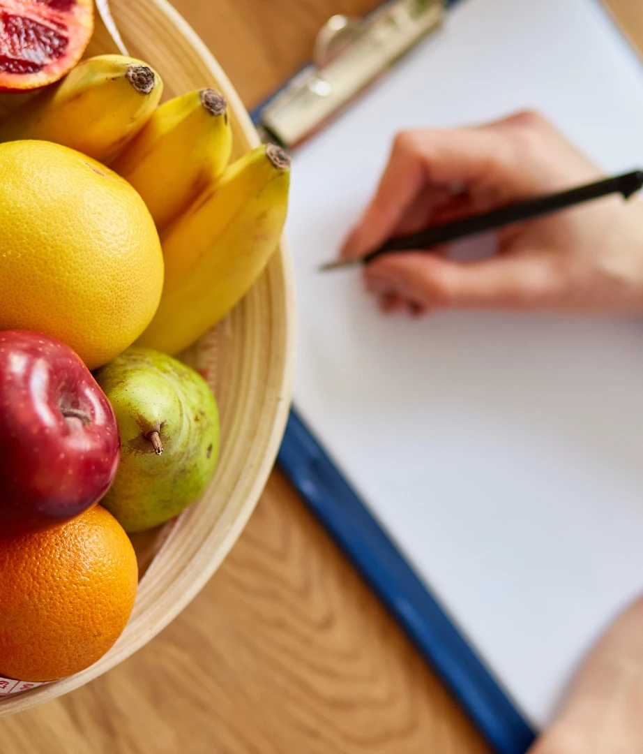 In a weight loss clinic in Vancouver, a bowl of fruit sits next to a hand writing on a piece of paper.