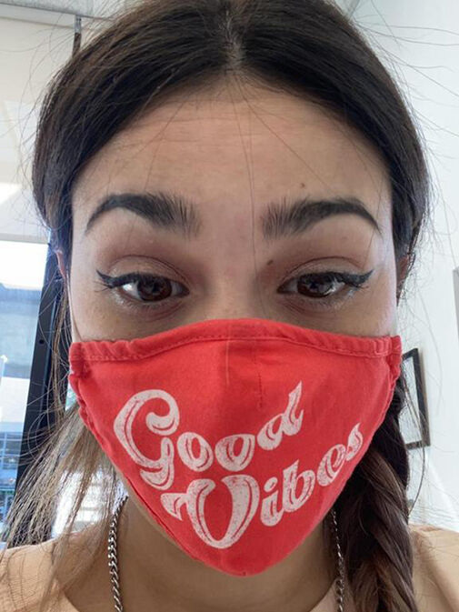 A person with dark hair wears a red face mask that reads "Good Vibes" in white script—perfect inspiration for our Before and After Gallery Vancouver.