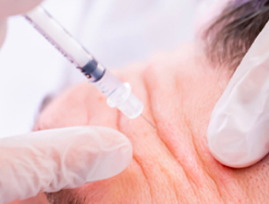 A close-up of a gloved hand injecting a syringe into the forehead of a person with visible wrinkles, highlighting advanced Medical Services Vancouver.