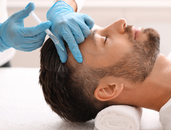 A man lying on a table with his eyes closed receives an injection in his forehead from a person wearing blue gloves, highlighting the professionalism of Medical Services Vancouver.
