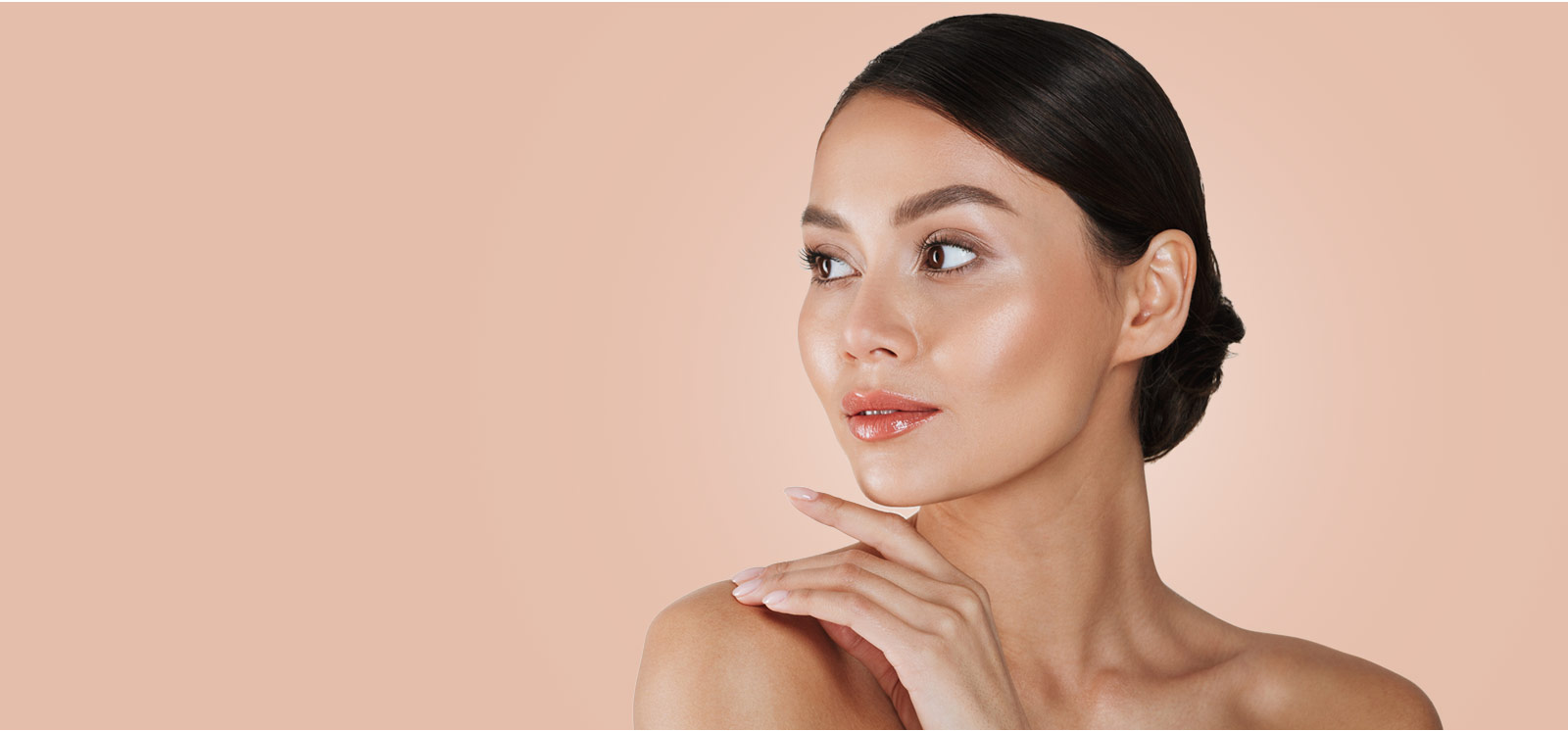 A woman is posing in front of a beige background.